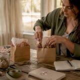 Hands assembling wedding welcome bags on table