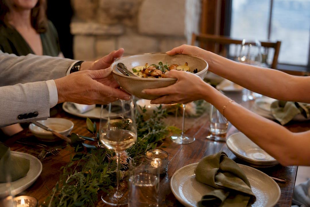 Guests passing shared dish at wedding meal