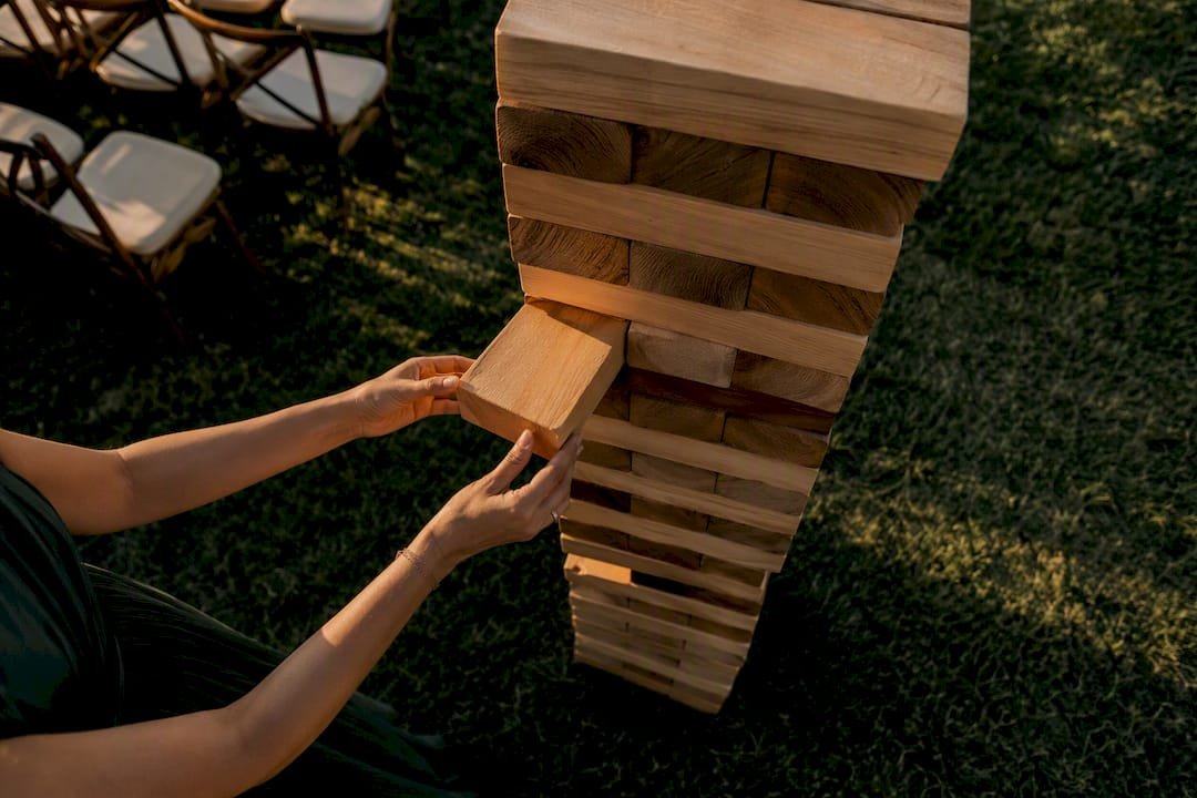 Hands removing block from giant Jenga tower